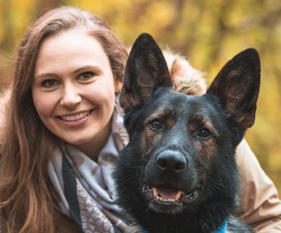 Luna sitzt aufrecht mit erhobenen Vorderpfoten im herbstlichen Wald